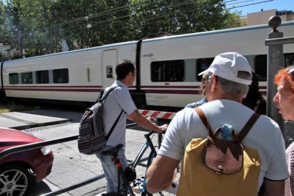 Vehículos y peatones esperan que pase el tren y se abran las barreras 